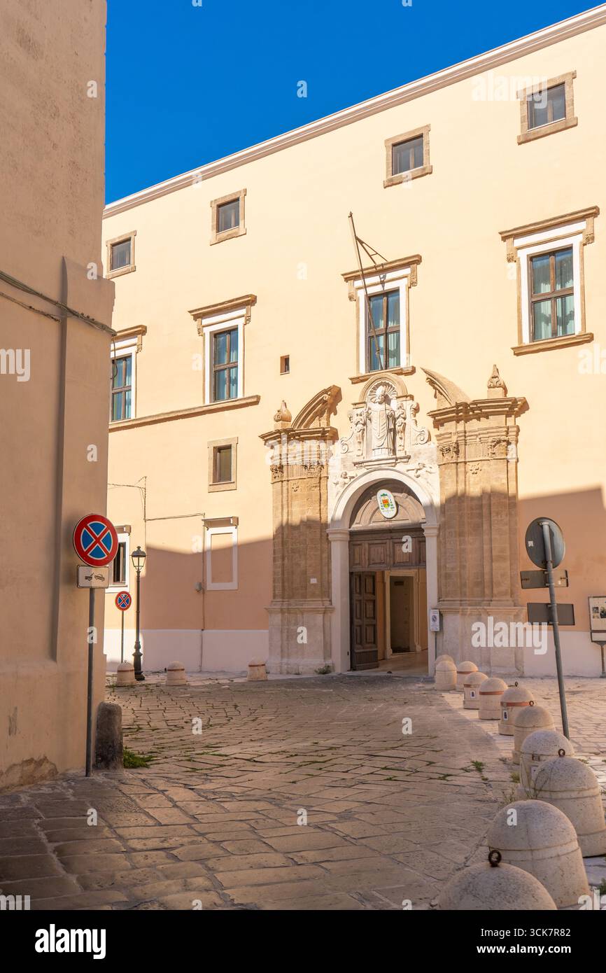 Palazzo Arcivescovile di Taranto nel centro storico (città vecchia), Puglia - portale barocco e vicolo in pietra sotto il cielo blu, Italia. Foto Stock