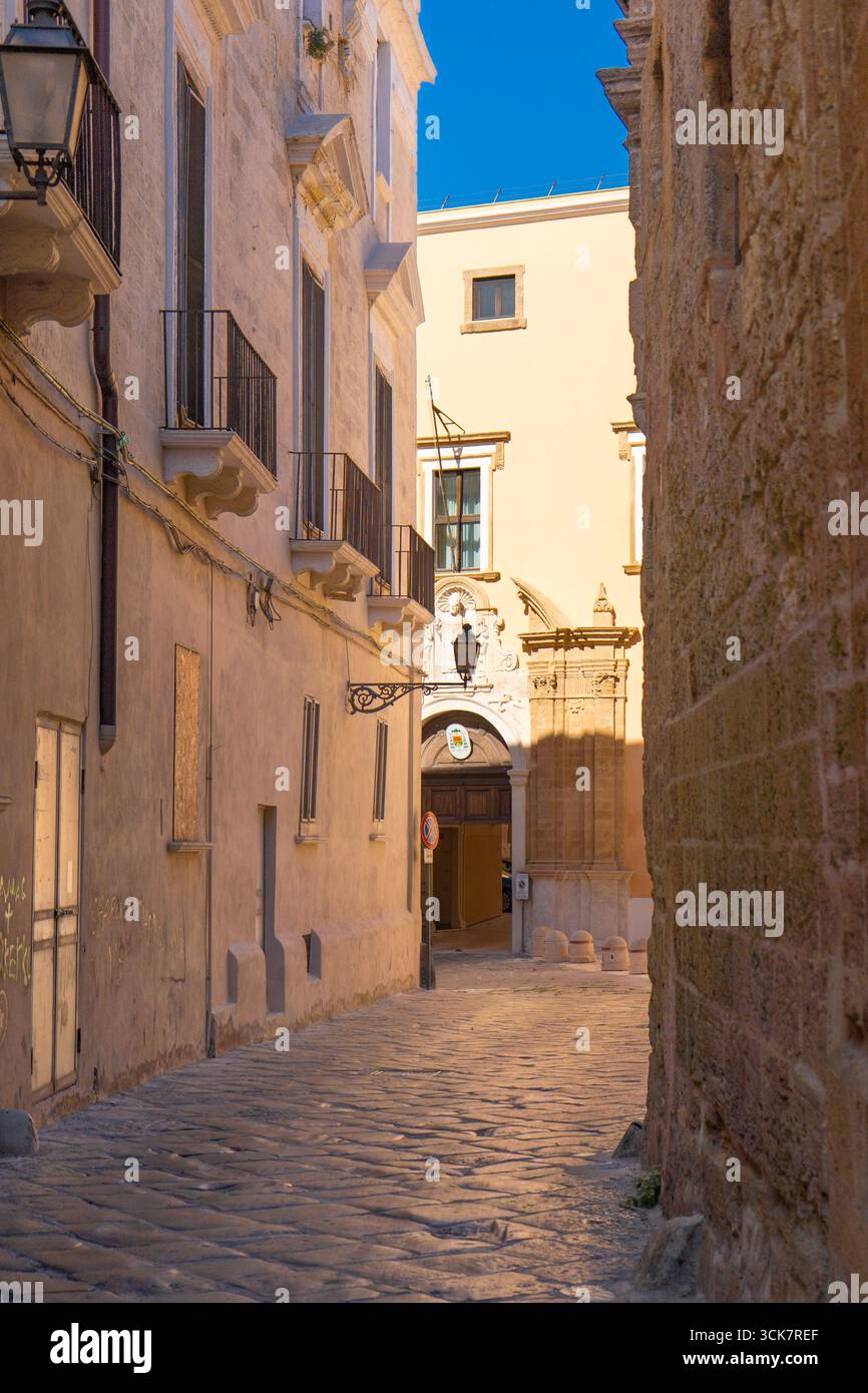 Palazzo Arcivescovile di Taranto nel centro storico (città vecchia), Puglia - portale barocco e vicolo in pietra sotto il cielo blu, Italia. Foto Stock