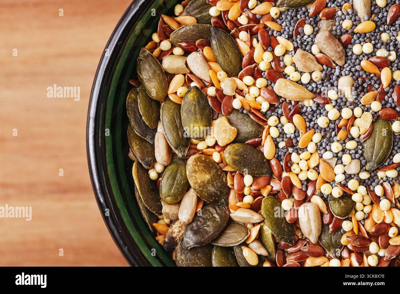 Mescolare i semi e i chicchi nel recipiente. Semi di zucca biologici, girasole e cereali. Cibo vegetariano sano background. Primo piano di semi naturali. Foto Stock