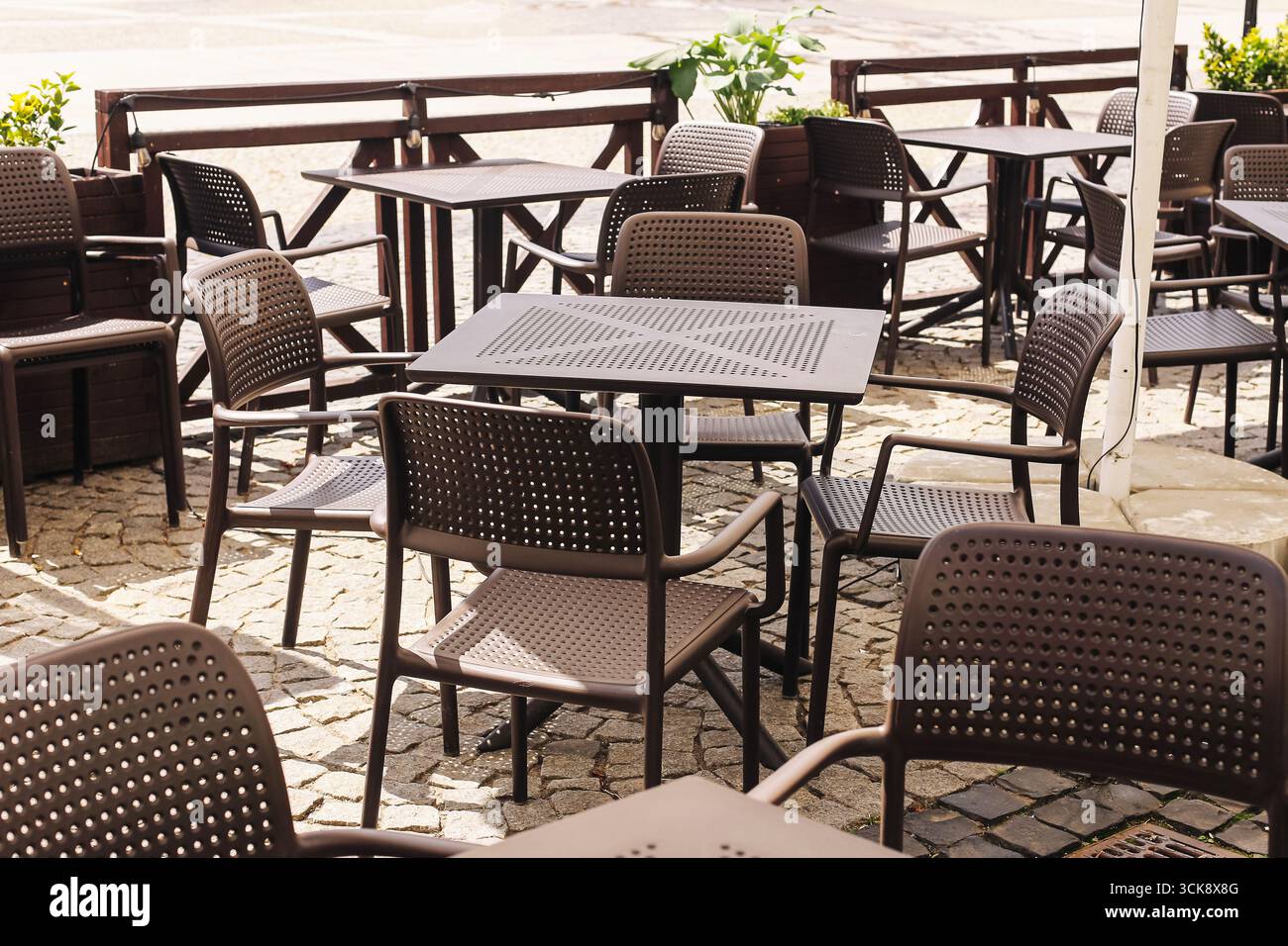 Terrazza con caffè all'aperto con tavoli e sedie. Fuori c'era un arredamento vuoto per il ristorante. Ristorante in strada nelle giornate di sole. Moderno ambiente urbano da caffe'. Foto Stock