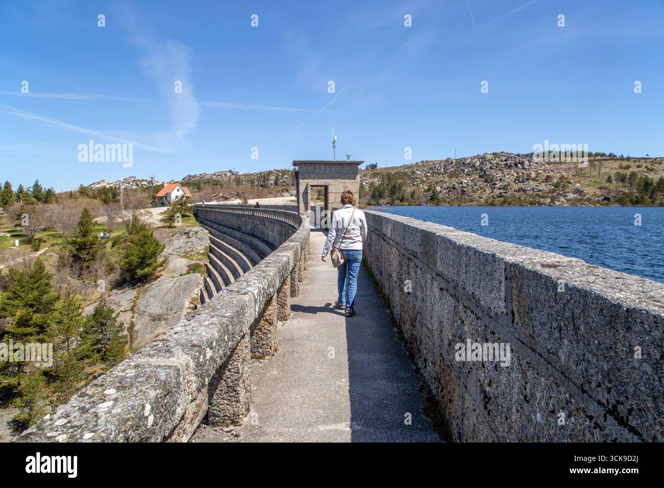 Donna che cammina sulla diga vale do Rossim, sulla laguna artificiale uno dei punti più alti del Portogallo Foto Stock