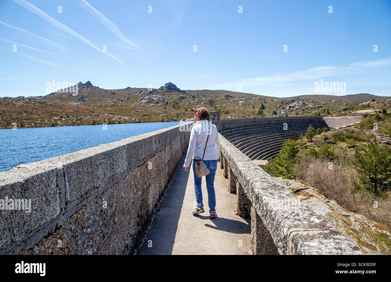 Donna che cammina sulla diga vale do Rossim, sulla laguna artificiale uno dei punti più alti del Portogallo Foto Stock