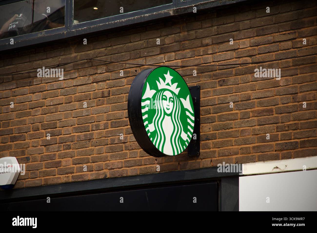 Un cartello con la caffetteria Starbucks su un muro di mattoni in una strada urbana, fotografata alla luce del giorno. Solo per uso editoriale. Foto Stock