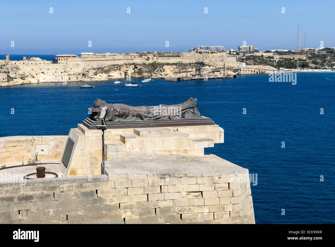 Memoriale del soldato addormentato della seconda guerra mondiale visto dai giardini Lower Barrakka con Fort Ricasoli sullo sfondo, la Valletta, Malta Foto Stock