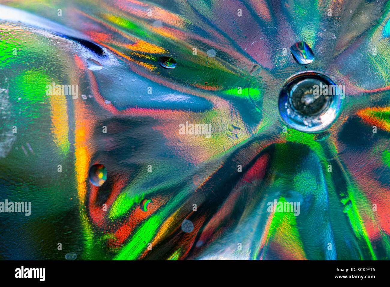 Un vivace primo piano di vetro di cristallo sotto la luce diretta, che mostra rifrazioni radiose e motivi astratti in tonalità rosso, blu, verde, giallo e arancione Foto Stock