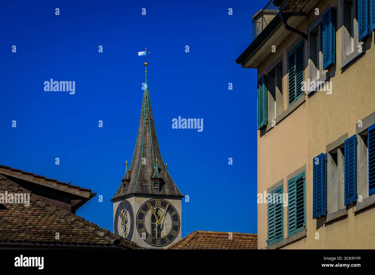 L'iconica torre dell'orologio della Chiesa di San Pietro incorniciata da edifici storici circostanti nella città vecchia o nell'Altstadt di Zurigo, Svizzera Foto Stock
