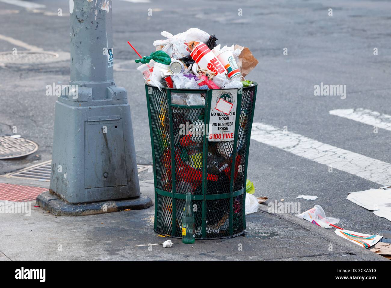 Una spazzatura sporca può essere riempita di rifiuti e spazzatura su un marciapiede di New York. Foto Stock