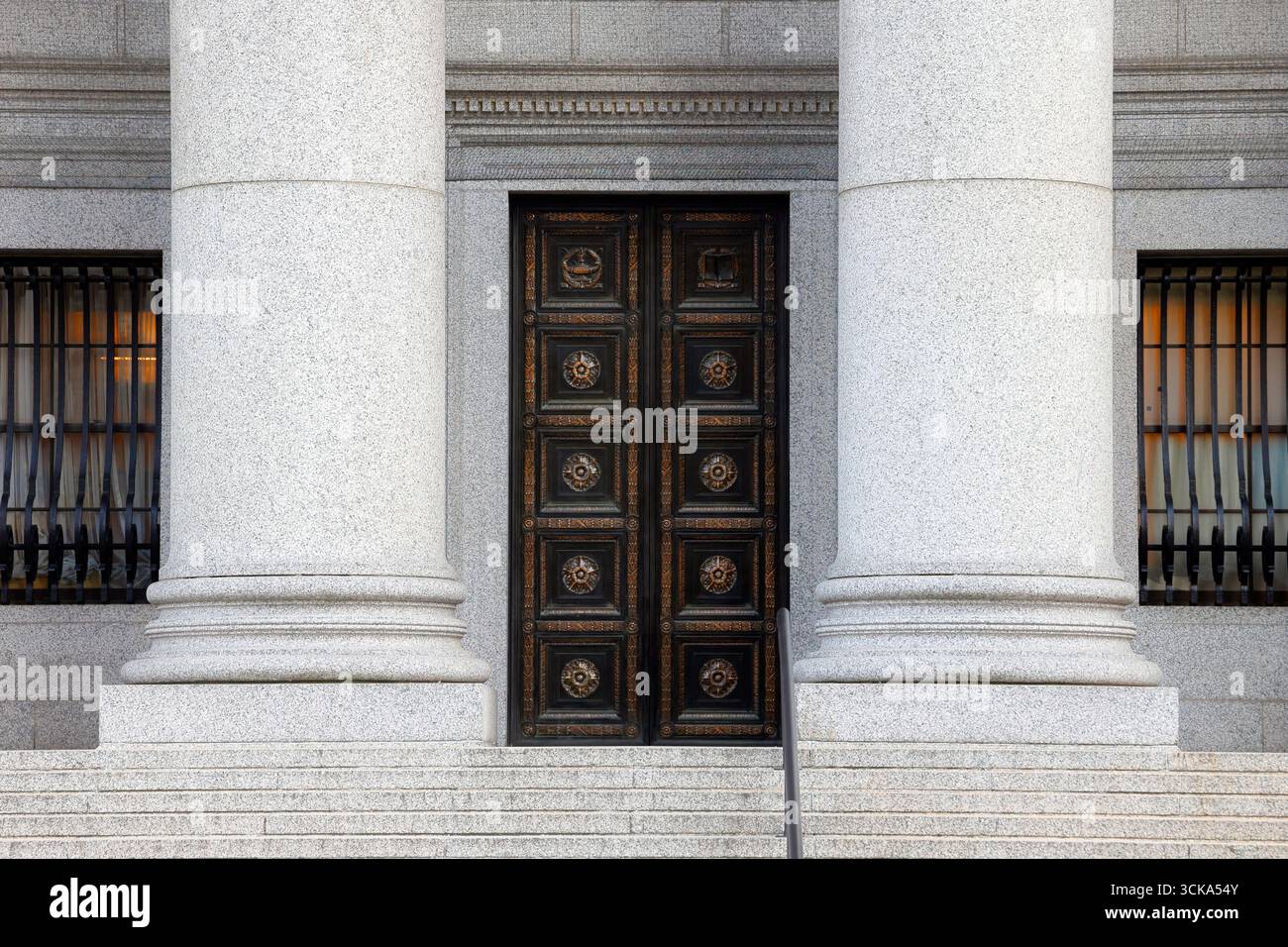 Gradini che conducono ad una porta di metallo ornata tra due grandi colonne di pietra in un tribunale federale Foto Stock