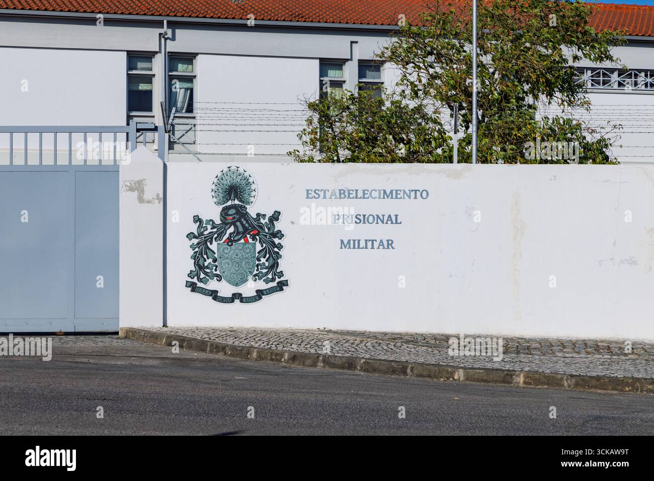 Una vista della prigione militare di Tomar, in Portogallo, che mostra la facciata bianca, un cancello chiuso e uno stemma. Tomar, Portogallo. 7 agosto 2025. Foto Stock