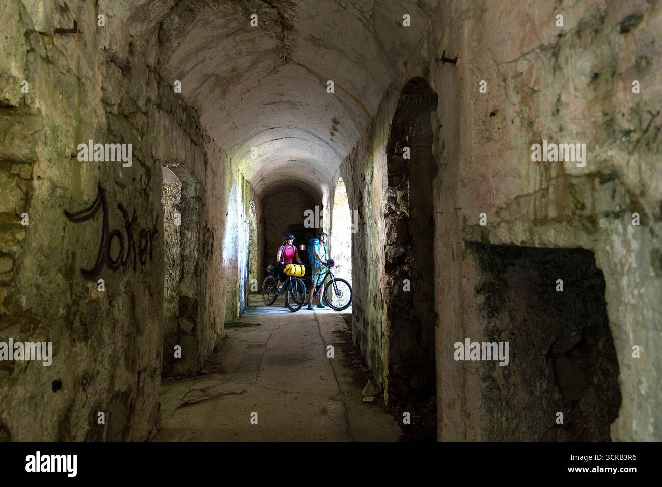 Turista in un viaggio in bicicletta e bikepacking in Slovenia, esplorando i resti di una fortezza italiana di una prima Guerra Mondiale sul passo di montagna predel in italia Foto Stock