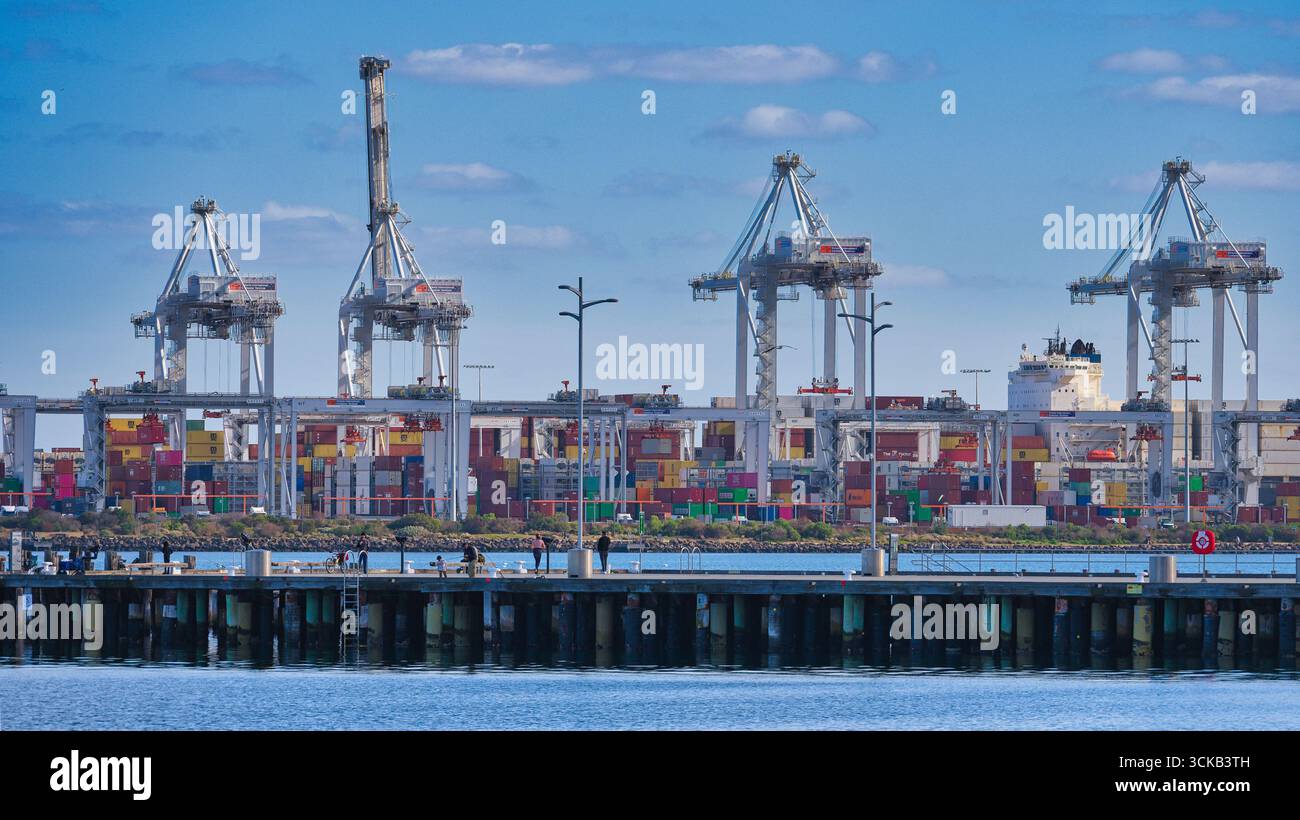 Porto di Melbourne, Victoria, Australia - 18 luglio 2025: Gru e container di spedizione presso Webb Dock visti dal molo dall'altra parte dell'acqua Foto Stock