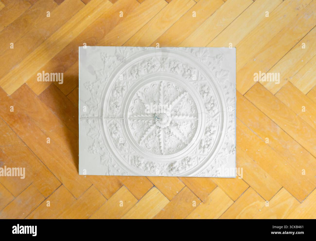 Riflesso scenografico dello stucco del soffitto in uno specchio adagiato su un parquet a spina di pesce Foto Stock