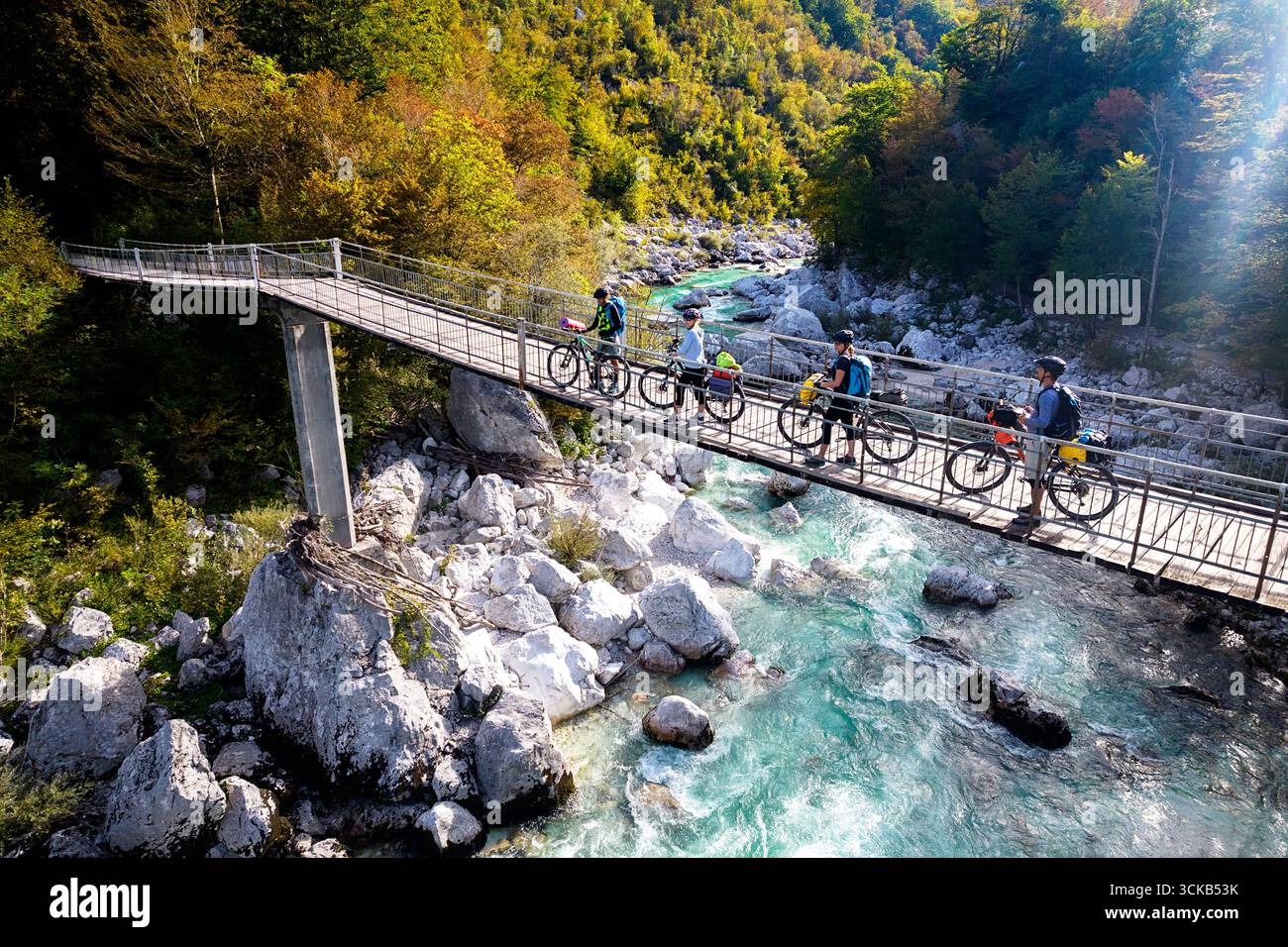 Turisti in un viaggio in bicicletta e in bicicletta in Slovenia, esplorando il bellissimo paesaggio montano, attraversando il ponte sospeso sul fiume soca vicino a kobarid Foto Stock