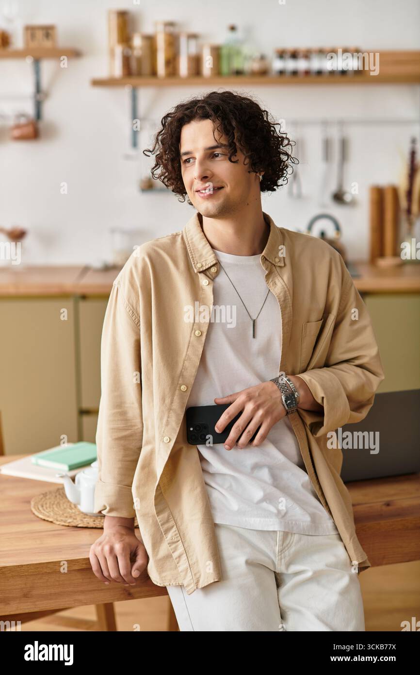 Bel giovane uomo in un abbigliamento casual per affari si appoggia su un tavolo di legno, sorridendo con gioia. Foto Stock