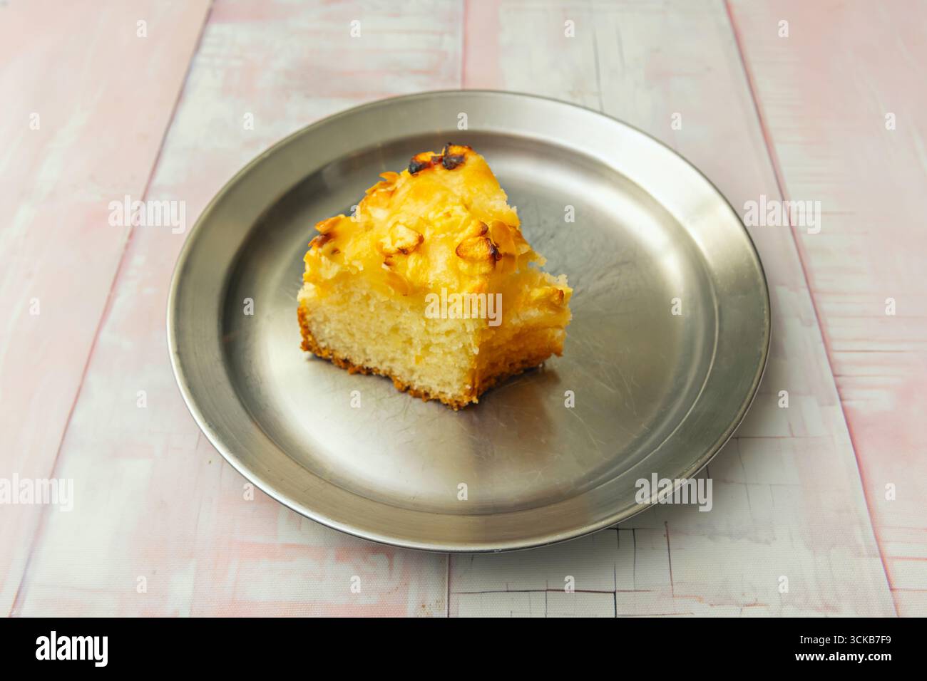 Soffice torta di spugna alla vaniglia con un intenso aroma naturale, decorata con raffinati scaglie di cioccolato bianco e una glassa fondente lucida. Foto Stock