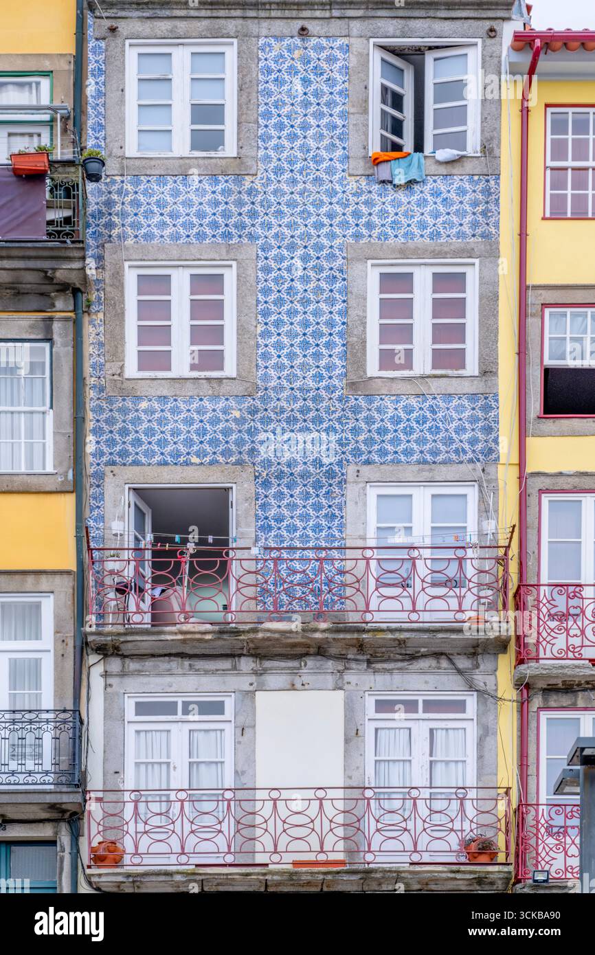 Facciata residenziale frammentata con Azulejos Blu, pareti gialle e balconi rossi ornati a Porto, Portogallo. contrasto urbano, diversità architettonica Foto Stock