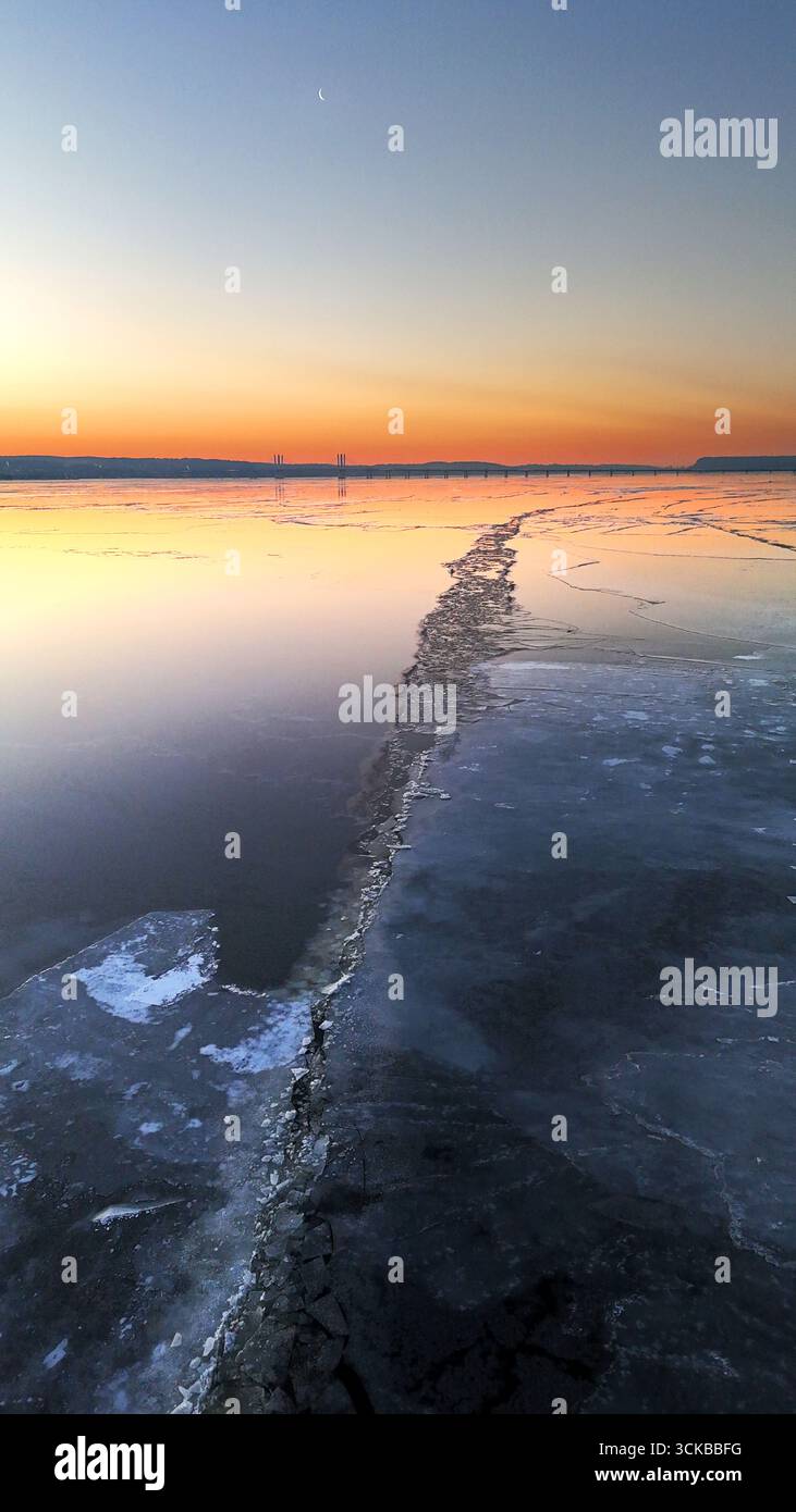 Vista aerea della distesa ghiacciata che riflette un tramonto sfumato che bacia l'orizzonte, un paesaggio da sogno invernale si dispiega vicino a Nyack, New York, Stati Uniti. Foto Stock