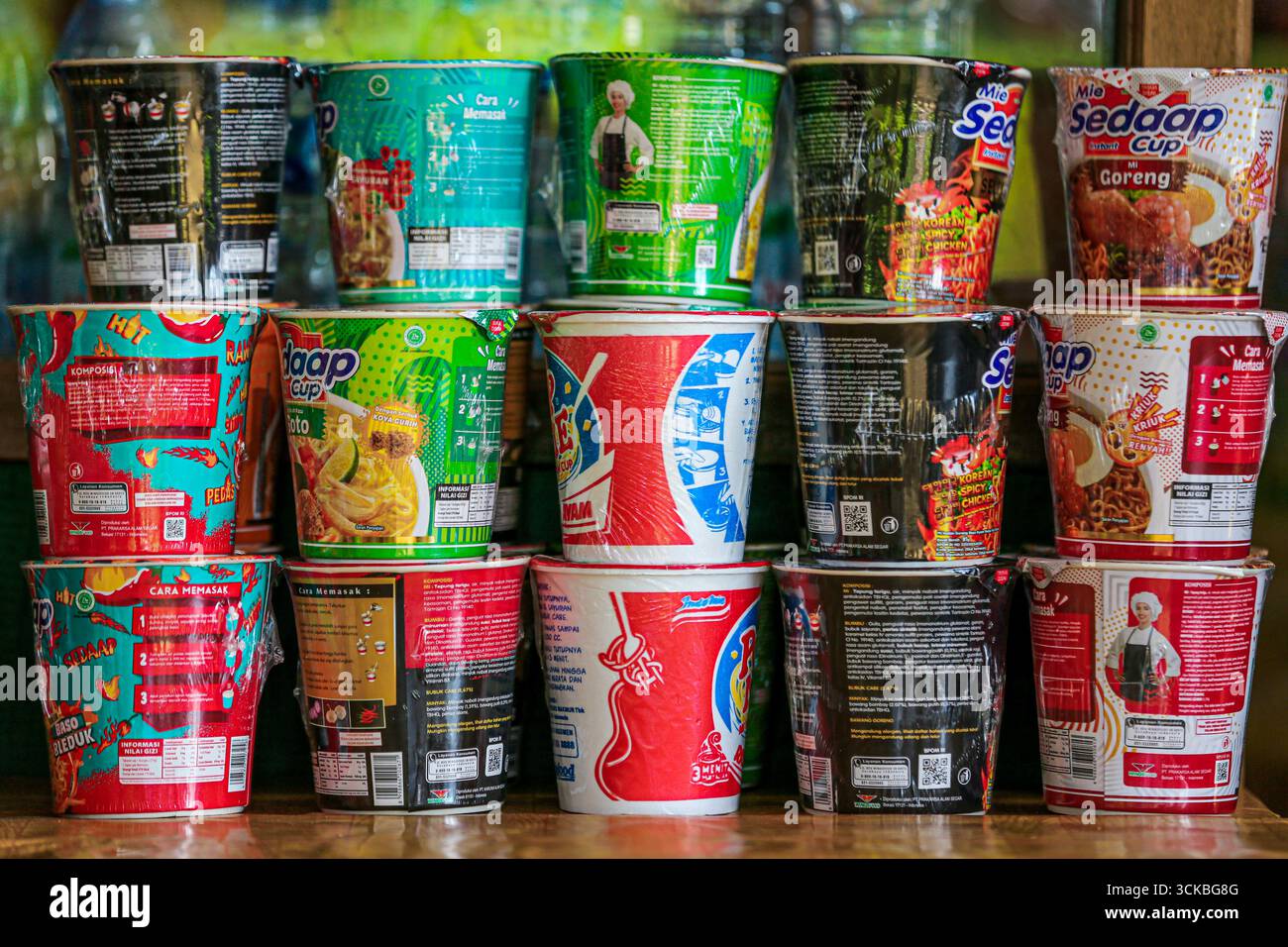 Una varietà di tazze di spaghetti istantanei impilate su uno scaffale, che presentano gusti diversi e confezioni colorate. Foto Stock