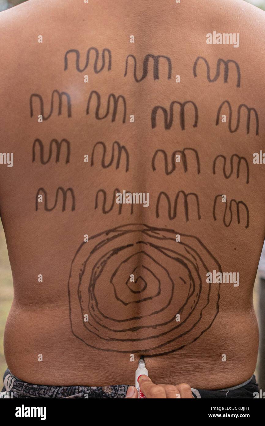 Primo piano della schiena di una persona con intricate opere d'arte del corpo tribale dalle linee ondulate e un design a spirale Foto Stock