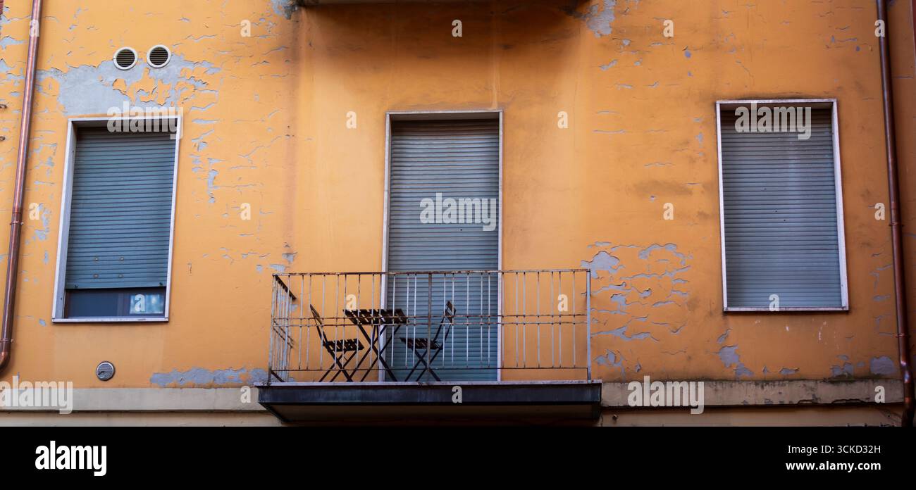 tre finestre con persiane e un balcone con tavolo e sedie Foto Stock