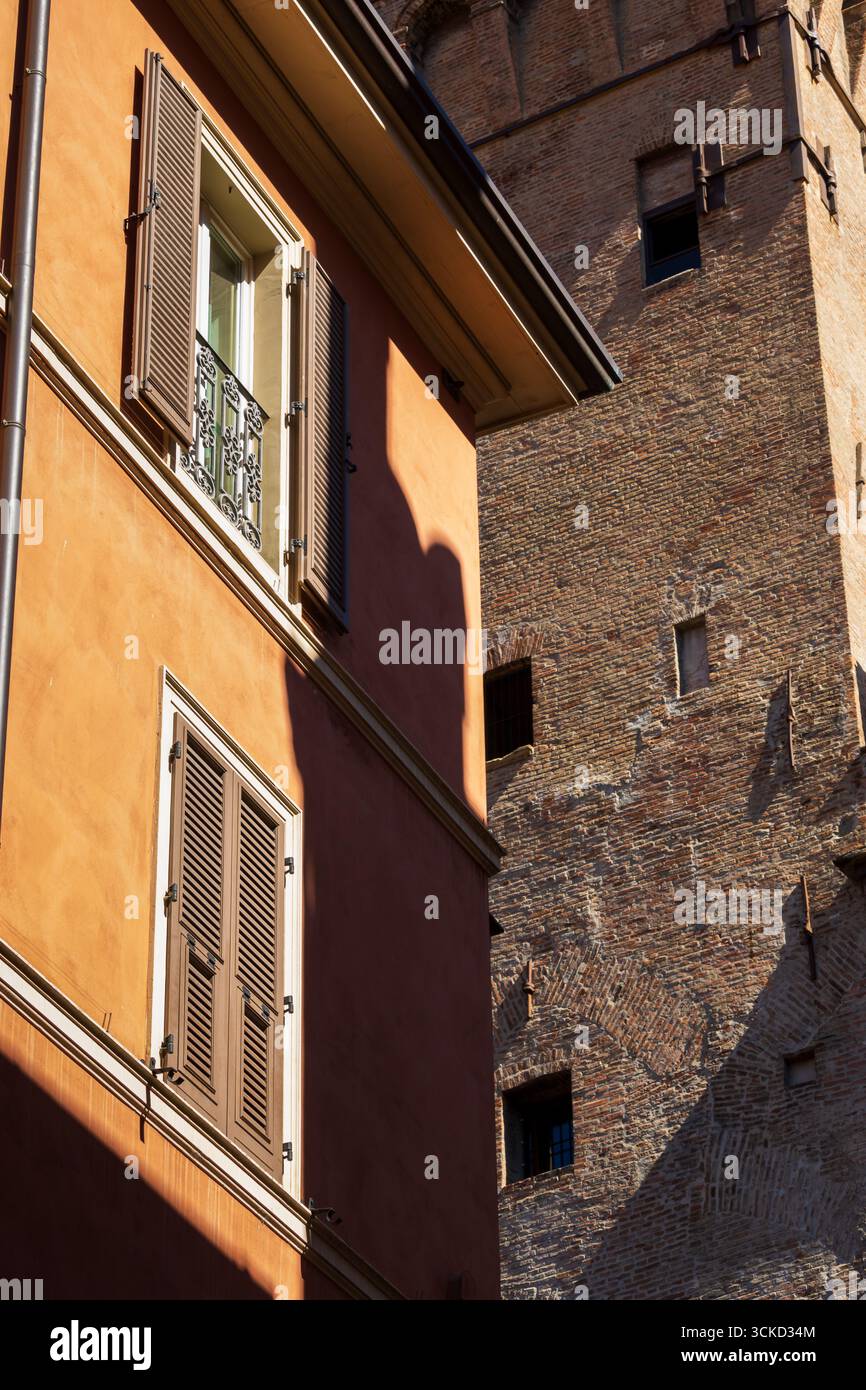 Facciata arancione con tapparelle di legno accanto al muro in mattoni invecchiati Foto Stock