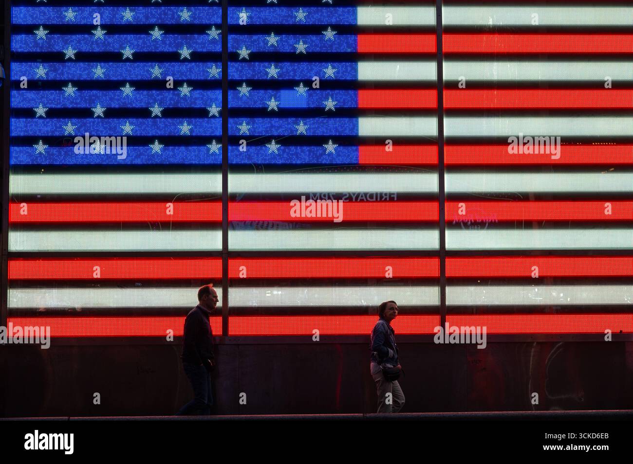 02.06.2025, Manhattan, New York, New York, Vereinigte Staaten USA - Menschen sind vor dem Hintergrund einer beleuchteten US-Flagge auf einer LED-Anzeige AM Times Square in Midtown Manhattan vor der Rekrutierungsstation der US-Streitkraefte zu sehen. *** 02 06 2025, Manhattan, New York City, New York, Stati Uniti gli Stati Uniti sono visti sullo sfondo di una bandiera statunitense illuminata su un display a LED a Times Square nel centro di Manhattan, di fronte alla US Armed Forces Recruiting Station Foto Stock