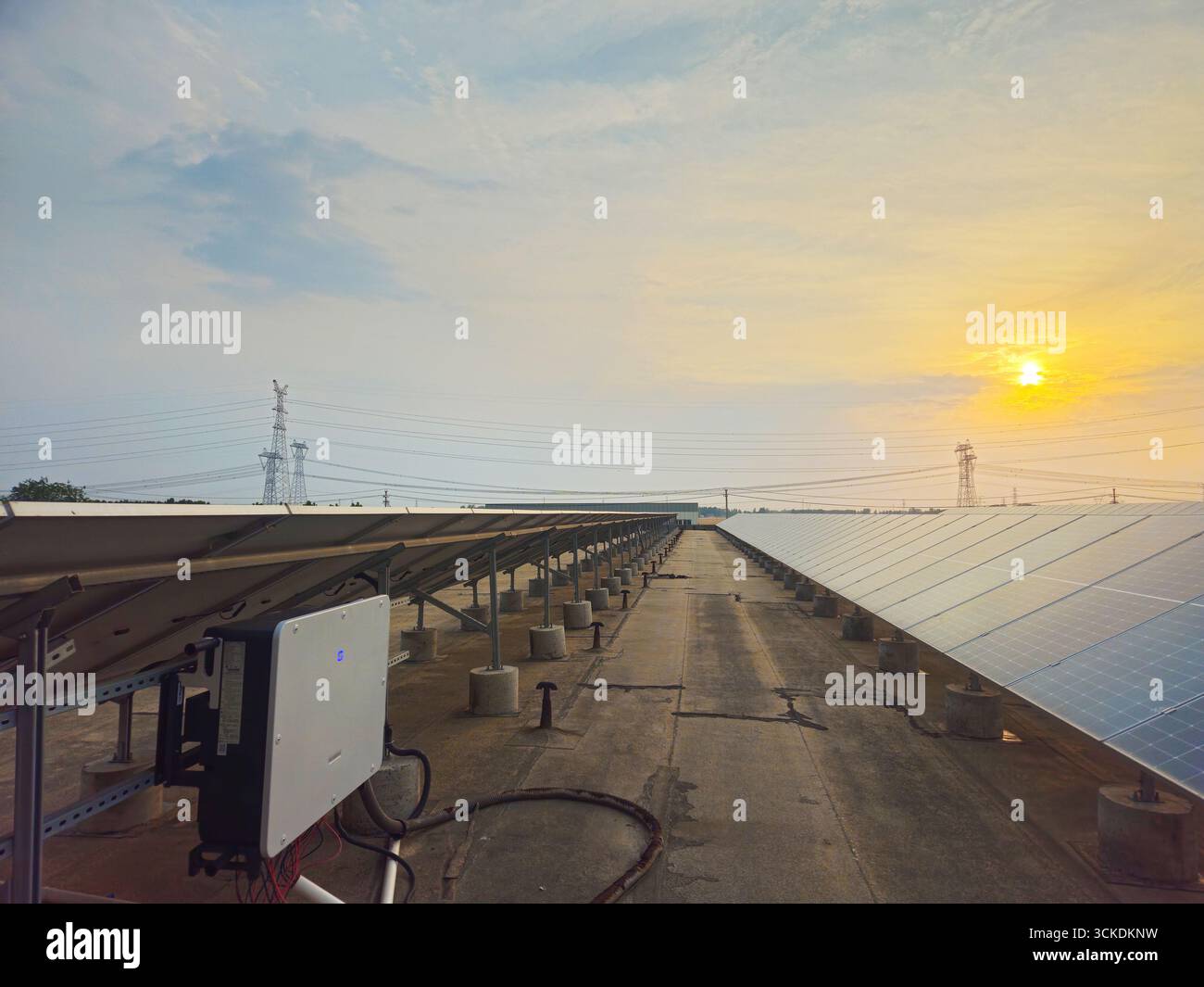 Array fotovoltaici solari sul tetto con inverter al tramonto Foto Stock