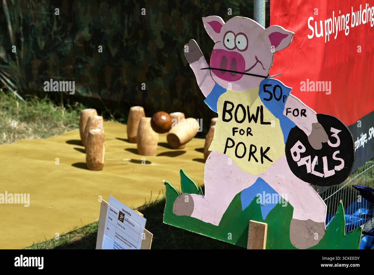 Palla che abbatte le birilli di legno a Un chiosco in una fiera inglese per vincere Un Joint of Meat, maiale con cartello pubblicitario Shape of A Pig, Fro Foto Stock