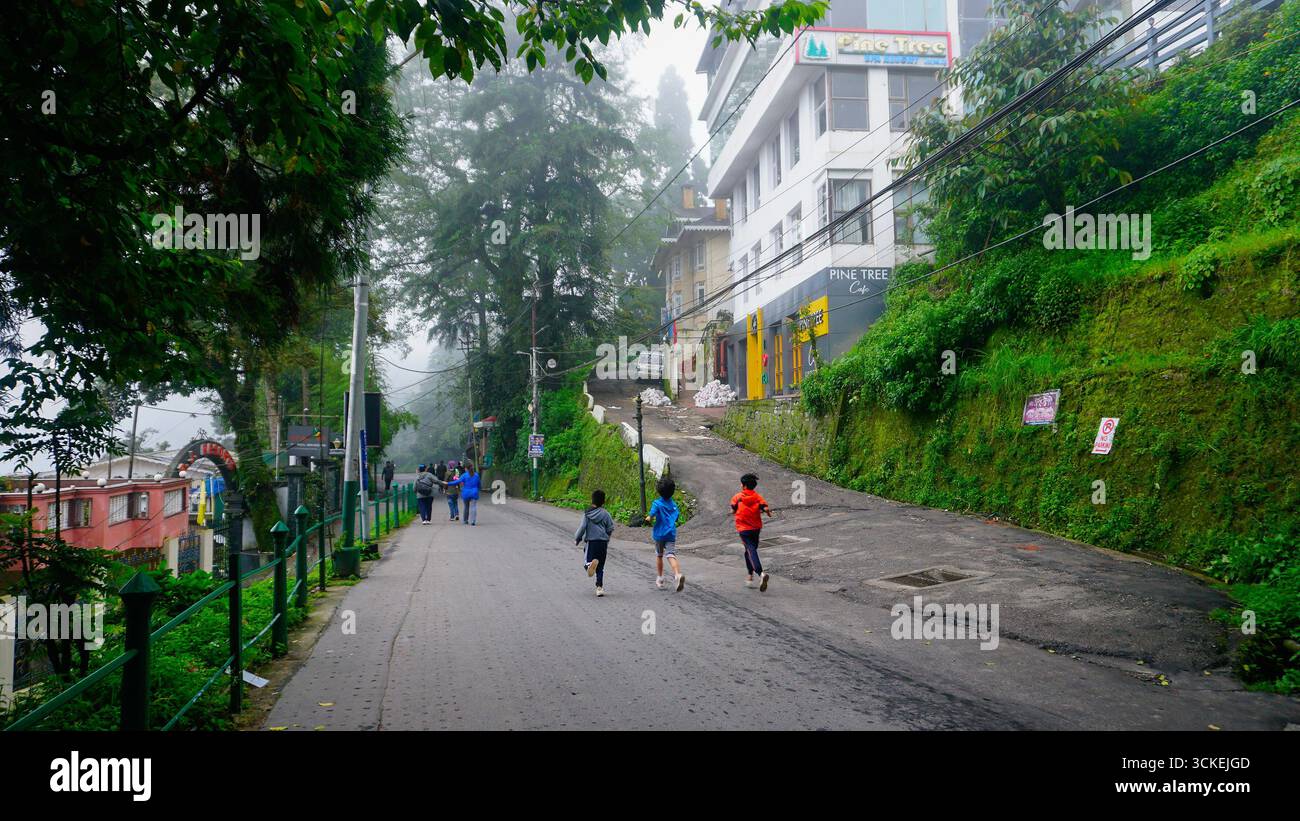 Kurseong, Darjeeling, Bengala Occidentale, India - 10.08.2023 : bambini che corrono sulla strada himalayana, bellezza panoramica di Kurseong, un luogo turistico molto popolare. Foto Stock