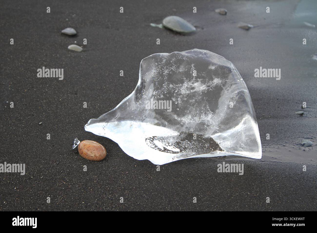 Frammento di ghiaccio del ghiacciaio che risplende come un gioiello naturale sulla sabbia vulcanica nera di Diamond Beach, Islanda, fotografato ad agosto. Foto Stock