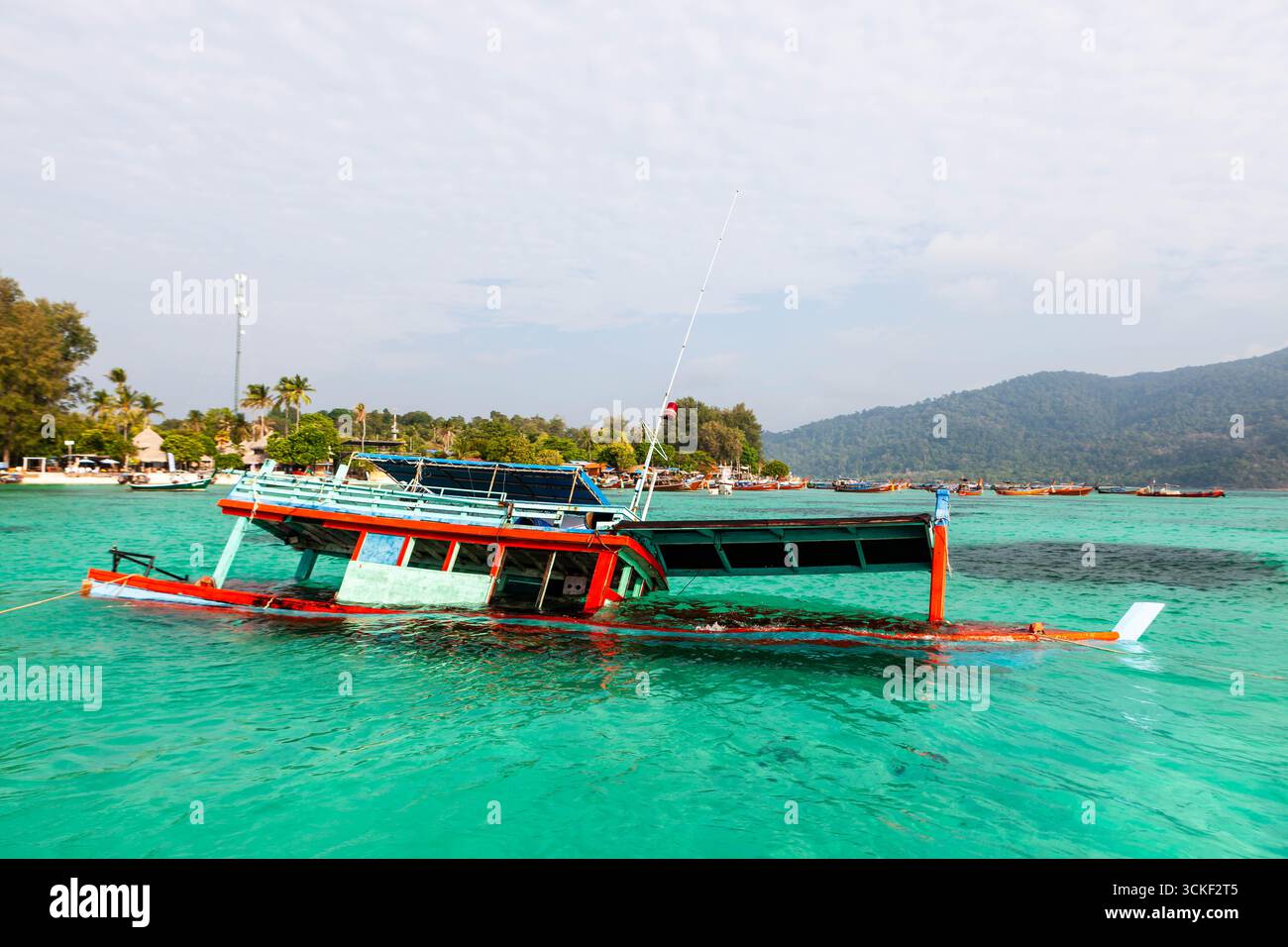 Koh Lipe, Thailandia. Barca a coda lunga affondata, un'imbarcazione naufragata in un mare cristallino color smeraldo. Paesaggio tropicale dell'isola, incidente, barca abbandonata. Foto Stock