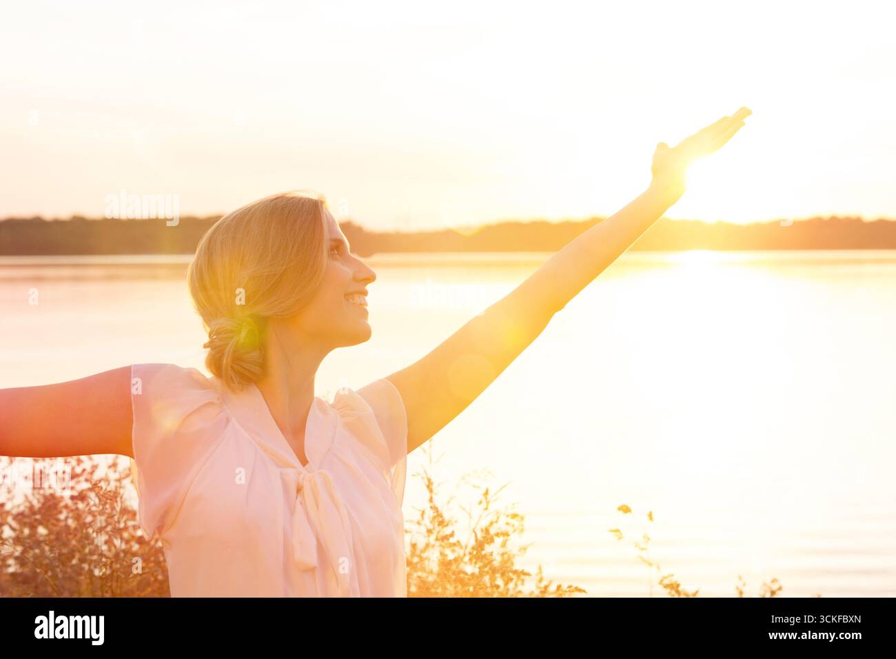 giovane donna contro la luce che fa un esercizio di meditazione Foto Stock