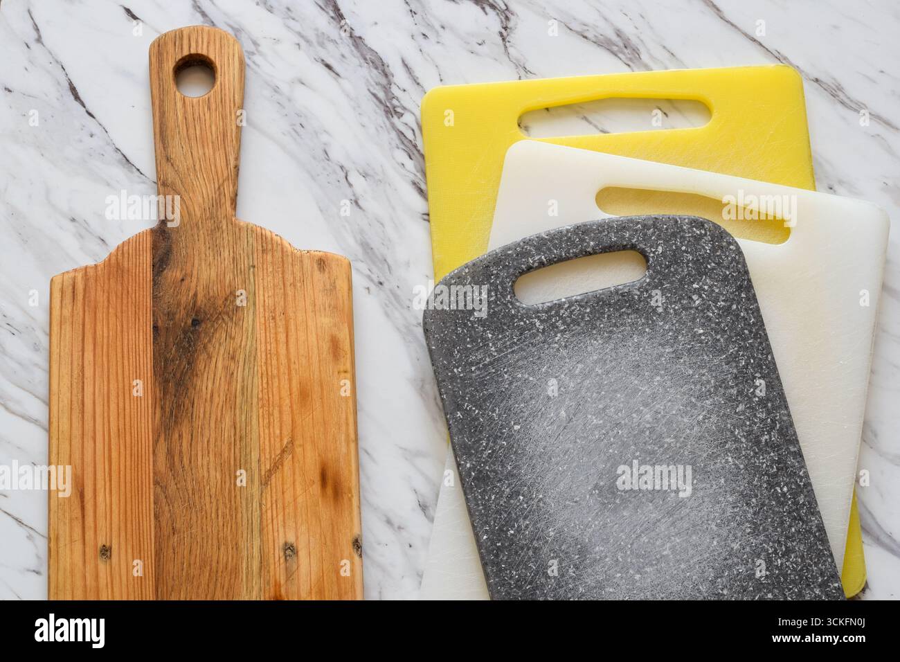 Vista laterale dei taglieri in legno e plastica. Concetto di scelta della cucina, igiene, sicurezza alimentare, sostenibilità e preferenze domestiche Foto Stock