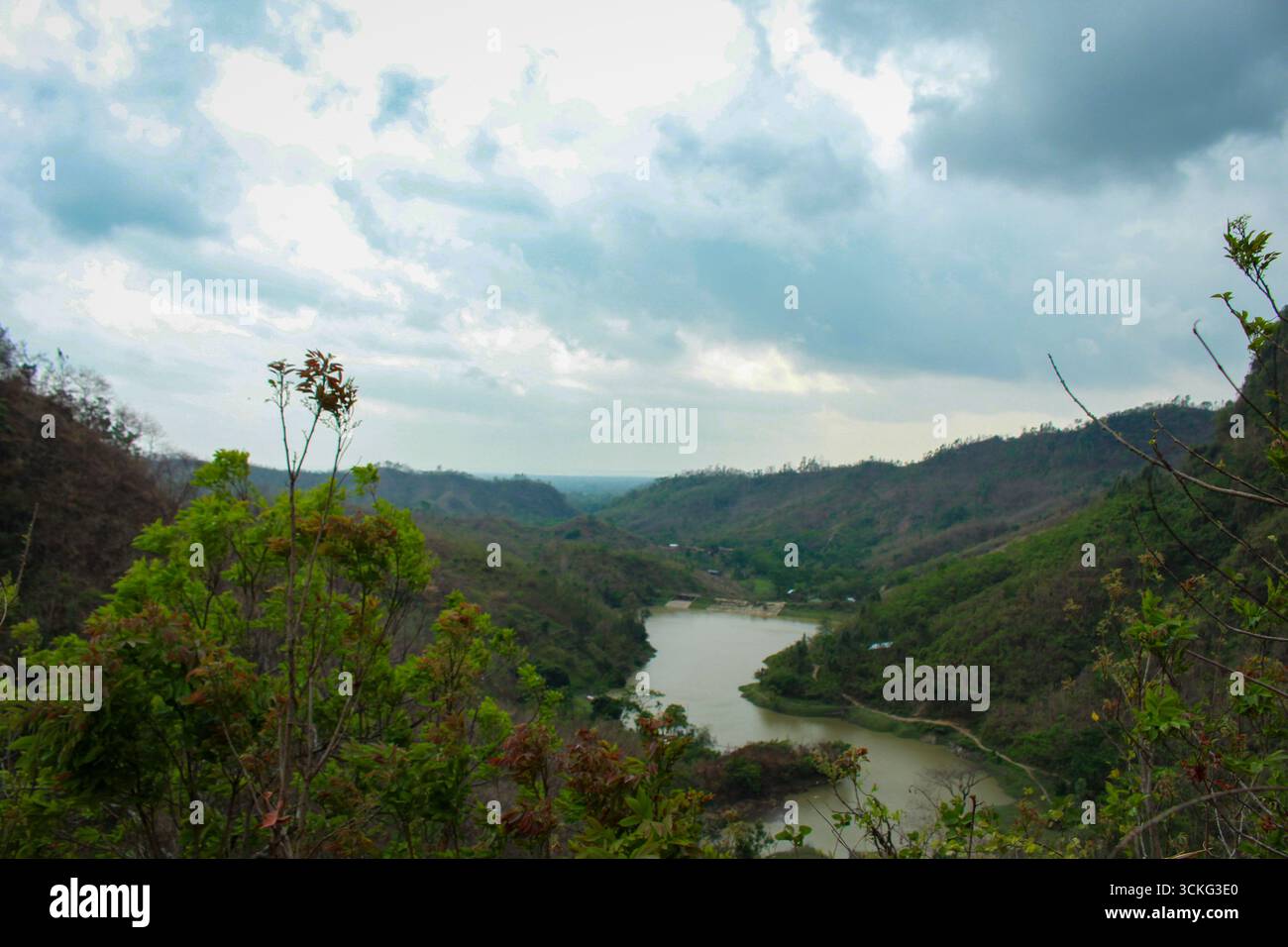 Una splendida vista di un fiume tortuoso che scorre attraverso verdi colline, circondato da una fitta vegetazione e da spettacolari cieli nuvolosi, creando un tranquillo ambiente naturale Foto Stock