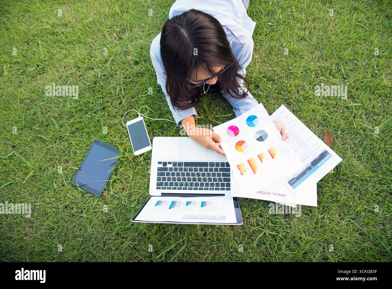 Donna asiatica stendersi parco verde giardino utilizzando computer portatile che lavora all'aperto casa ufficio. La felicità della donna sorride lavorando freelance su un notebook. Giovani donne Univer Foto Stock