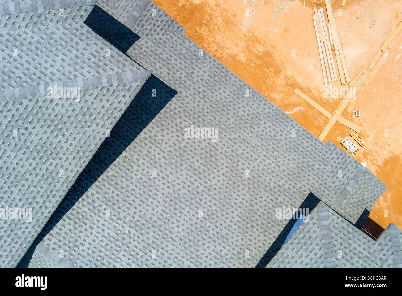 Vista aerea lavori di copertura di edifici residenziali presso il cantiere con materiali sparsi intorno. Foto Stock