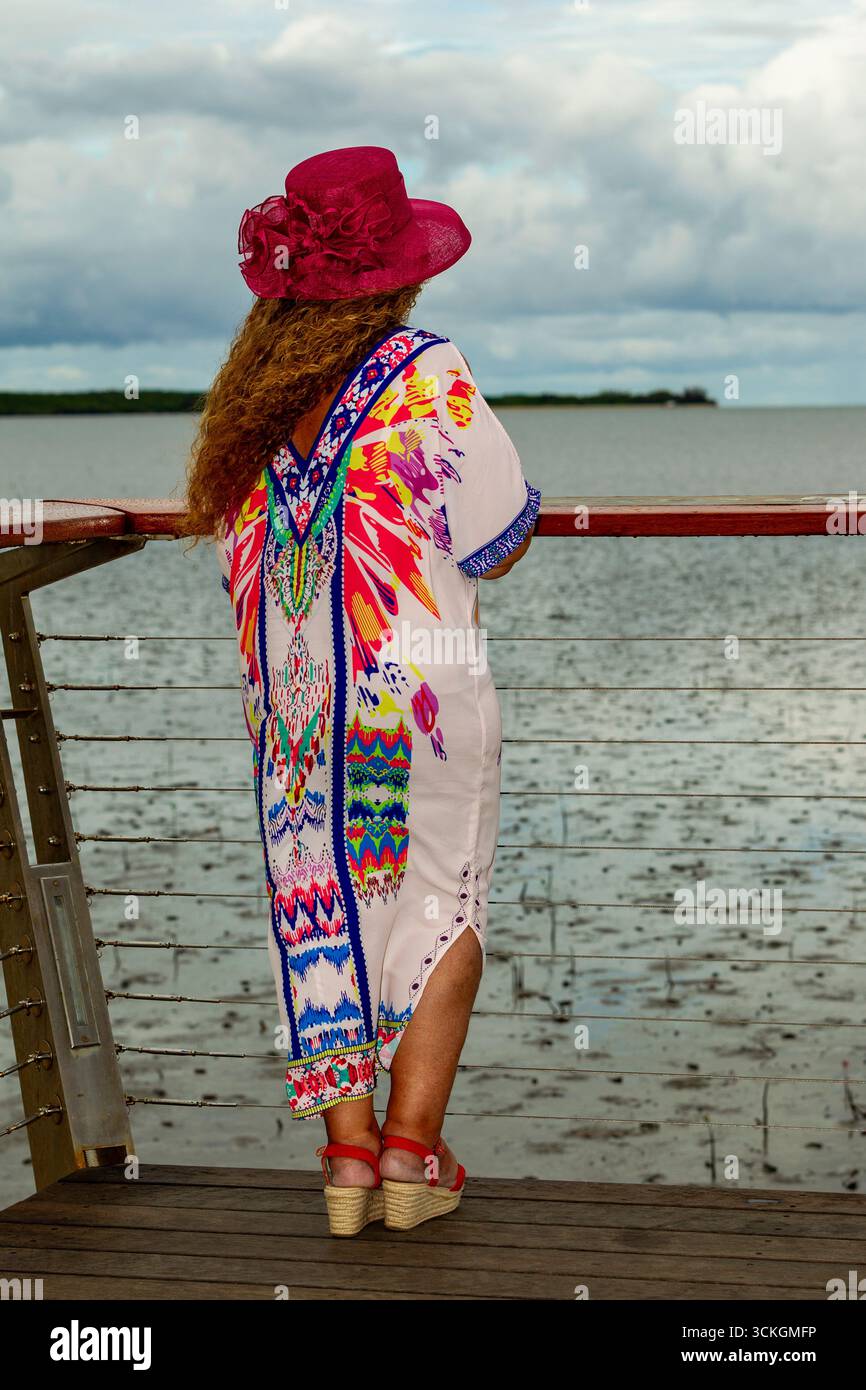 cappello rosa lady lookout vestito colorato cappello di mare che guarda sul retro capelli lunghi ricci capelli marroni 50 più modelli di modelli maturi che modellano australia au Foto Stock
