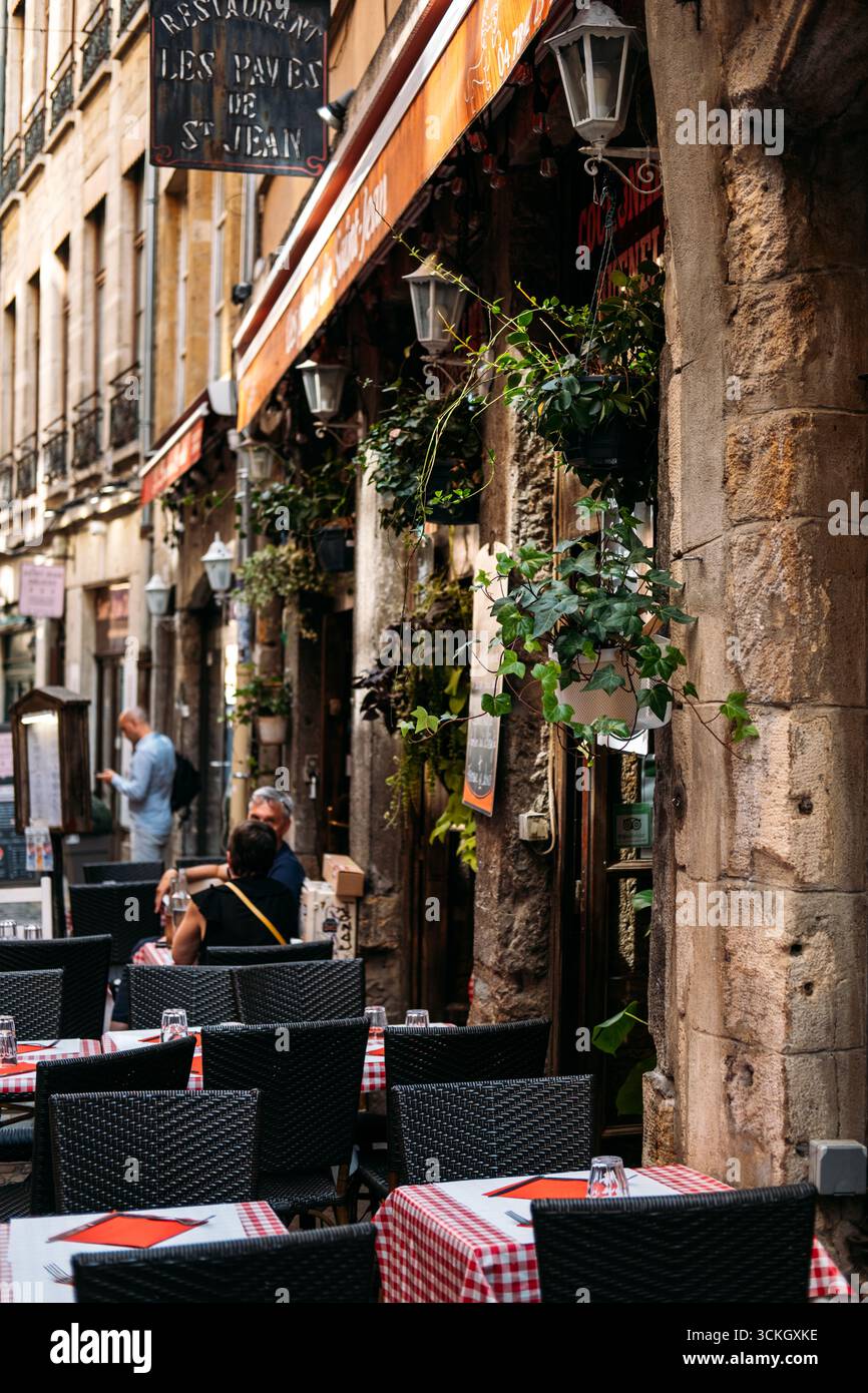 Terrazza all'aperto del ristorante Les Paves de Saint Jean con tovaglie rosse a scacchi e facciata rustica in pietra nel quartiere storico di Vieux Foto Stock
