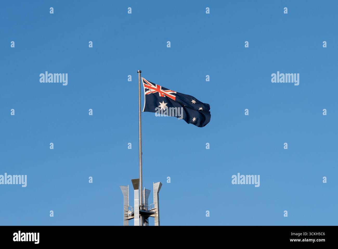 La bandiera dell'Australia sventolava con il cielo blu sullo sfondo in cima all'Australia Parliament Building, Canberra, Australia. Foto Stock