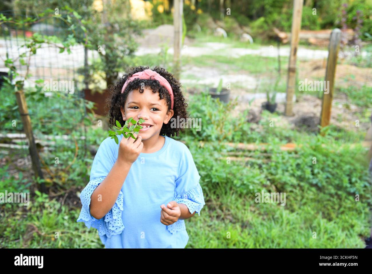 Il bambino puzza di piante da giardino mentre esplora una fattoria della Florida centrale Foto Stock
