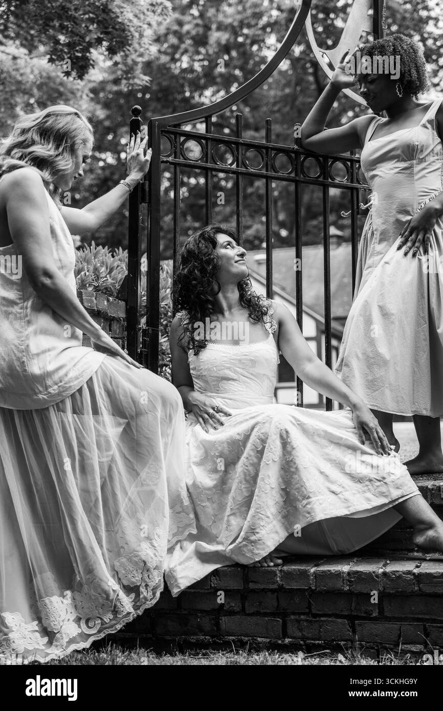 Tre donne in abiti eleganti posano insieme in bianco e nero Foto Stock