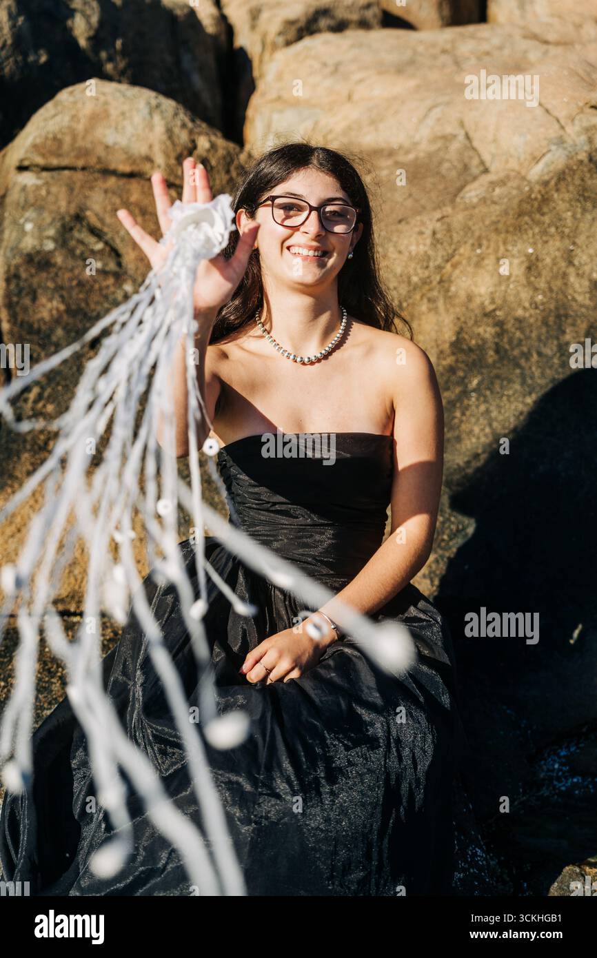 Giovane modello che mostra reti fantasma bagnate a terra su rocce Foto Stock