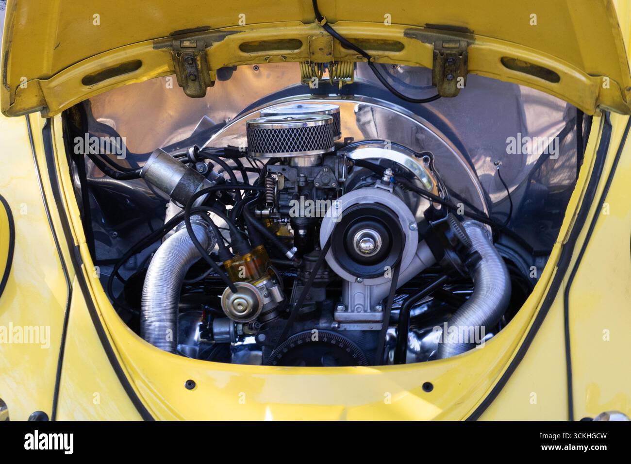 Cofano aperto che mostra il motore di un'auto gialla d'epoca, evidenziandone la meccanica e il design Foto Stock