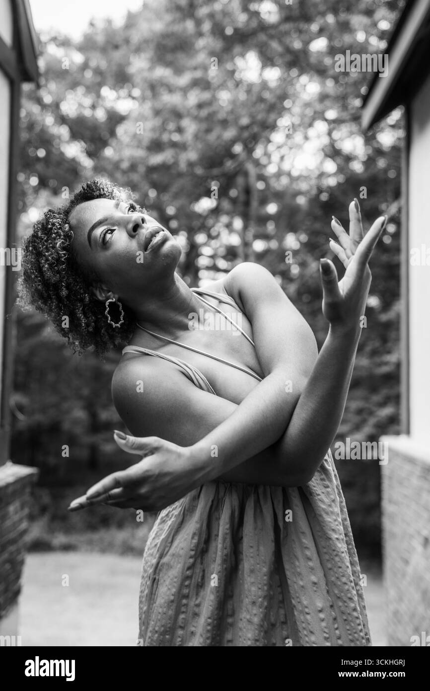 Ritratto in bianco e nero di una donna in posa di danza espressiva all'aperto Foto Stock