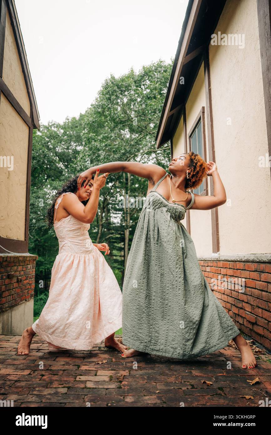 Due donne con abiti lunghi eseguono danza espressiva all'aperto Foto Stock