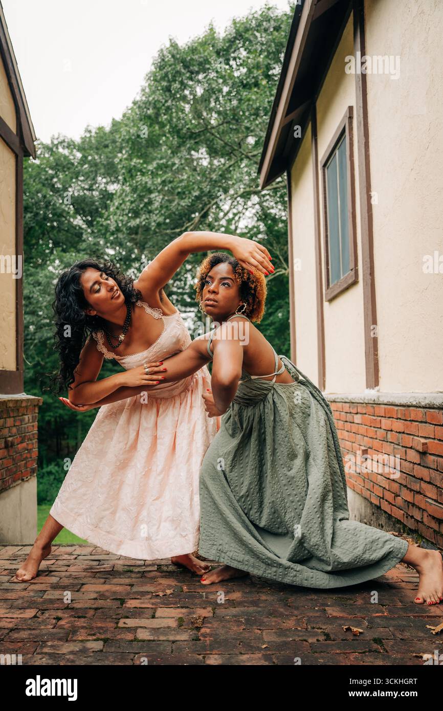Due donne in abiti fluenti posano in una danza espressiva all'aperto Foto Stock