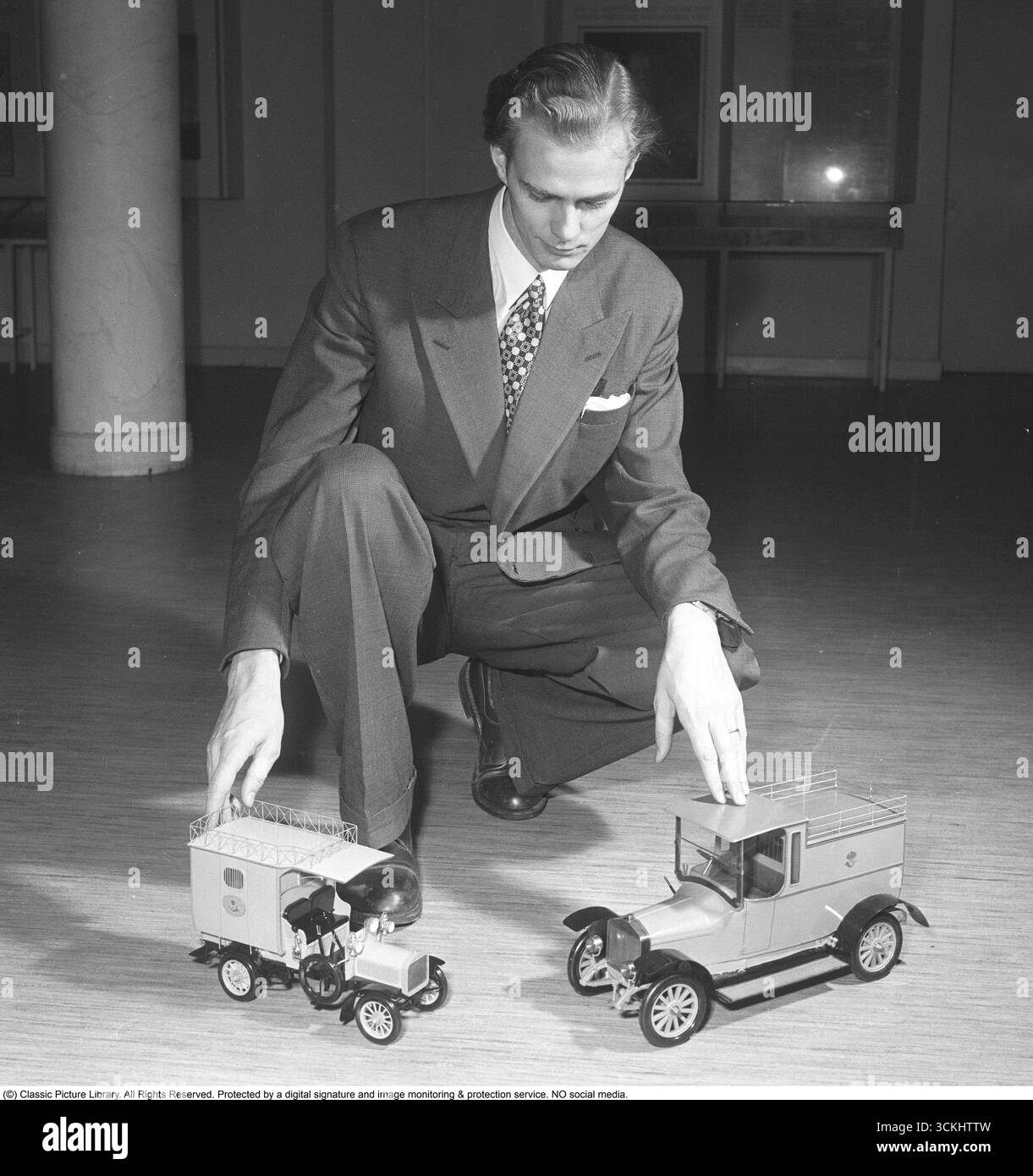 Negli anni '1950 Un uomo con due macchinine giocattolo davanti a lui sul pavimento. I giocattoli sono mezzi di trasporto utilizzati dai servizi postali. 1950. Kristoffersson rif. BB32-9 Foto Stock Negli anni '1950 Un uomo con due macchinine giocattolo davanti a lui sul pavimento. I giocattoli sono mezzi di trasporto utilizzati dai servizi postali. 1950. Kristoffersson rif. BB32-9 Foto Stock