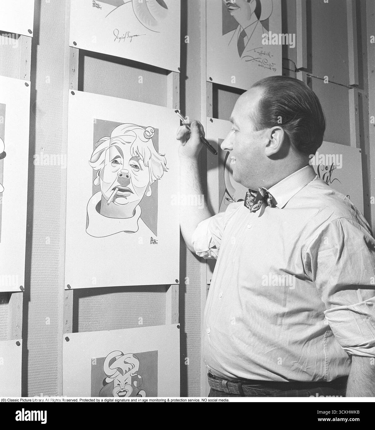 Al Bergström (1910-1975), caricaturista svedese, è catturato nel parco divertimenti Gröna Lund a Stoccolma nel 1950. Conosciuto per i suoi disegni spiritosi, intratteneva i visitatori con il suo stile artistico unico. Caricaturists come Bergström erano popolari animatori nei parchi di divertimento, offrendo schizzi personalizzati che catturavano lo spirito del turismo e dell'umorismo della metà del XX secolo. Sta guardando il suo ritratto di Naima Wifstrand. (Kristoffersson, rif. AY63-2) Foto Stock