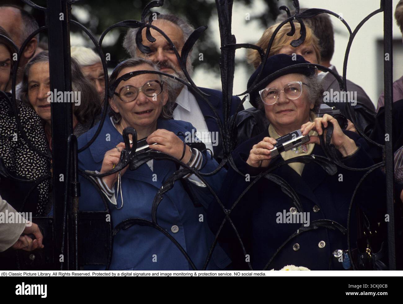 Pronti con la fotocamera. Due donne anziane sono pronte con le loro telecamere analogiche per catturare il momento in cui i reali passano e possono scattare una foto. 1985 Foto Stock
