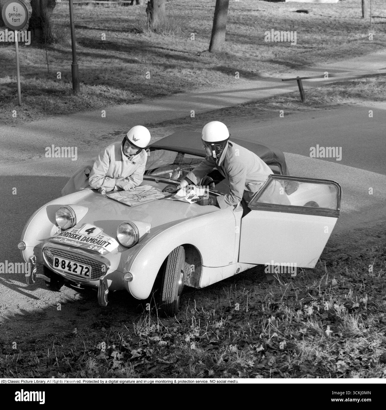 Austin-Healey Sprite MK1 Frogeye: Icona del Rally Spirit degli anni '1960. In questa vibrante immagine del 1960 del Nordic Women's Rally, due partecipanti femminili si trovano accanto alla Austin-Healey Sprite MK1 "Frogeye", un'auto sportiva britannica compatta celebrata per i suoi fari sgargianti e simili a rane e per il rivoluzionario design monoscocca. Lanciata nel 1958 da Donald Healey Motor Company sotto la guida di BMC, la Sprite offriva un divertimento accessibile con un motore da 948 cc serie A da 43 cv, trazione posteriore e un telaio leggero da 1.500 lb, ideale per una guida vivace e per gli sport motoristici. Il suo significato risiede nella democratizzazione dello sport CA Foto Stock